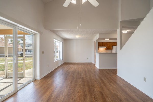 Undecorated Living Area With Hard Wood Flooring And A Glass Sliding Door To Outside